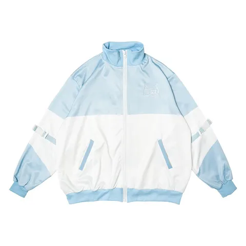 Product photograph: an oversized track jacket in pale blue and white with a small pixel-cat embroidery on the chest and a strap across each sleeve, on a white background.