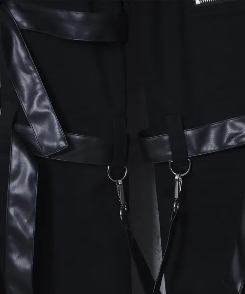 Close view of black trousers with leather belt straps, buckles and hanging metal rings.