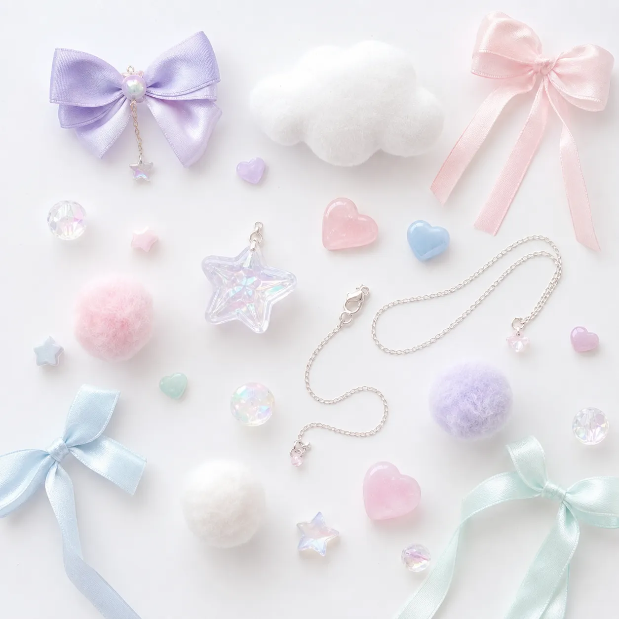 Generated editorial image: pastel ribbons in lavender, pink, blue and mint, a white felted cloud, iridescent star and heart charms, soft pom-poms and a fine silver chain, arranged on a white background.