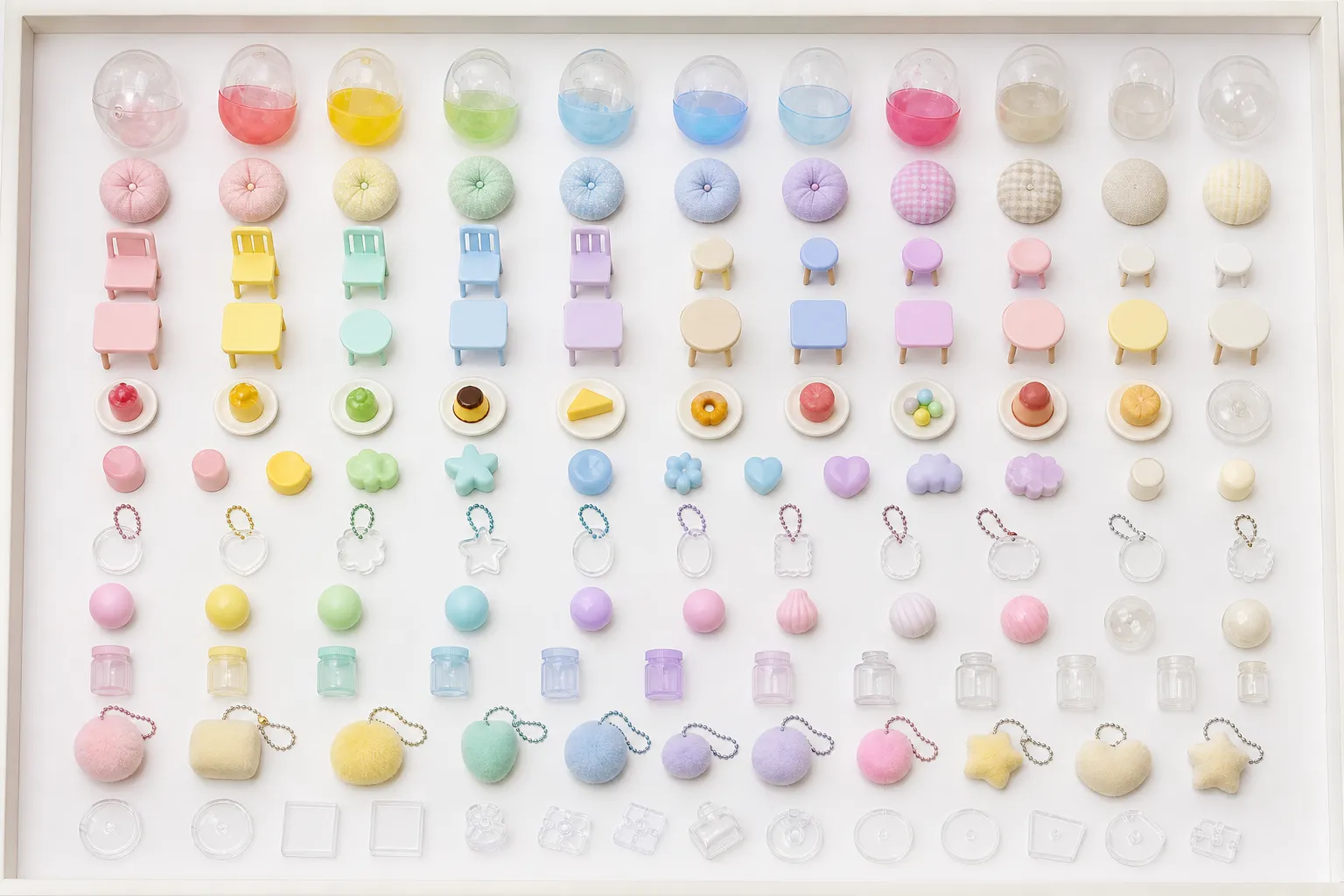 Generated editorial image: a framed specimen tray of Japanese capsule toys laid out in rows on white — clear capsule shells tinted in pastel colours, small round cushions, miniature chairs and tables, tiny food models on plates, plain resin charms, clear acrylic keychains, small spheres, miniature jars, pom-pom keyrings, and clear bases.